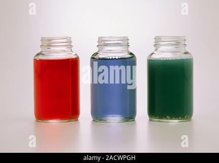 Three jars containing red cabbage juice, turned red by adding lemon (acid), green by adding soap (alkali), and blue with nothing added. Stock Photo