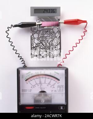 A solar cell inside a calculator connected to a multimeter, measuring the electricity generated. Stock Photo