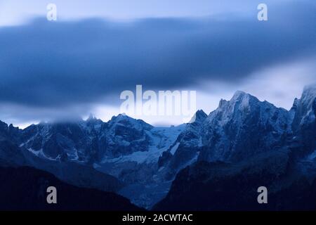 Clouds in the night sky over the rocky peak of Piz Cengalo, Tombal, Soglio, Val Bregaglia, canton of Graubunden, Switzerland Stock Photo