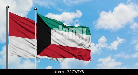 Kuwait and Monaco flag waving in the wind against white cloudy blue sky ...