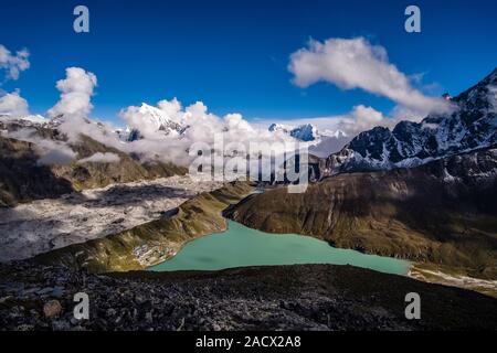 Panoramic aerial view over Gokyo Lake, Ngozumpa glacier and the village from the summit of Gokyo Ri, monsoon clouds moving in Stock Photo