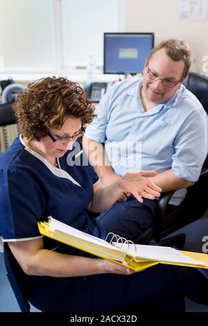 Doctor having a discussion with a practice nurse and going over some documents. Stock Photo