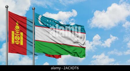 Mongolia and Uzbekistan flag waving in the wind against white cloudy blue sky together. Diplomacy concept, international relations. Stock Photo