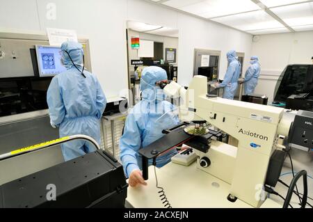 Silicon wafer research. Researchers working in a clean room to develop advanced silicon wafer technology. In electronics, a silicon wafer (round objec Stock Photo