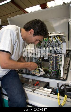 Installing electric circuits for a tram. Electrician working on the electrics of a tram. A tram is a vehicle that runs on rails in urban streets. Phot Stock Photo