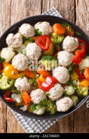 Vegetable soup with chicken meatballs close-up in a plate on the table. Vertical top view from above Stock Photo