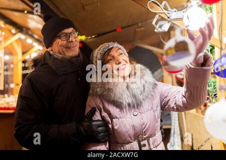 shopping, winter holidays and people concept - happy senior couple at christmas market souvenir shop on town hall square in tallinn, estonia Stock Photo