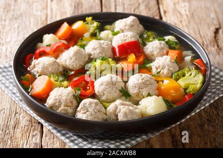 Broth with chicken meatballs and vegetables close-up in a plate on the table. horizontal Stock Photo