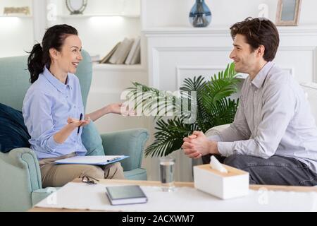 Relieved guy having pleasant conversation with psychologist Stock Photo