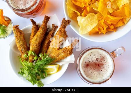 Mug with beer and beer snacks. Fried fish with chips and sauce. Stock Photo