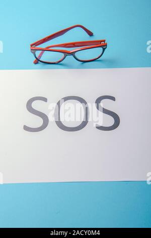 Word SOS written on white paper. Blue background Stock Photo