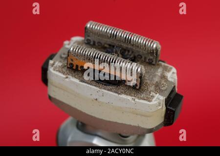 Closeup of dirty razors of foil electric shaver on red background Stock Photo