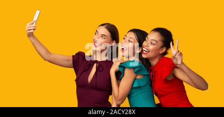 Three Millennial Girls Using Phone Making Selfie, Studio Shot, Panorama Stock Photo