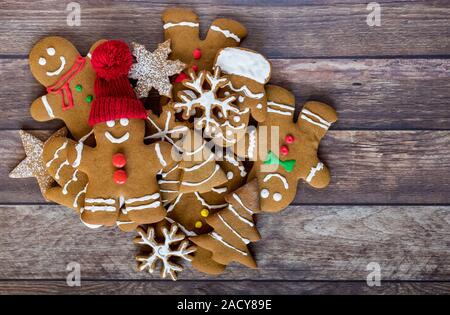 A top down view of a heaping pile of decorated gingerbread cookies with one on top wearing a toque. Stock Photo