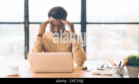 Exhausted millennial black businessman having migraine attack Stock Photo