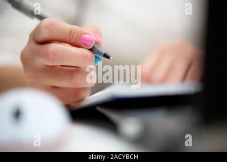 female hands with pen writing on notebook Stock Photo