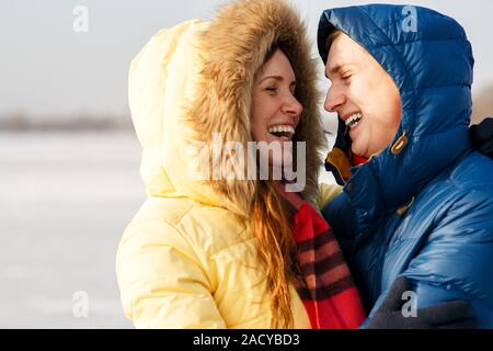 Happy Young Couple in Winter Park having fun.Family Outdoors. love kiss Stock Photo