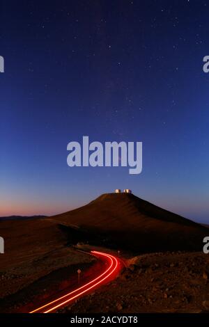Dawn sky over Paranal observatory. Time-exposure photograph of vehicle tail light trails along a road leading to the Cerro Paranal observatory in the Stock Photo