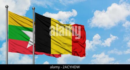 Belgium and Myanmar flag waving in the wind against white cloudy blue ...