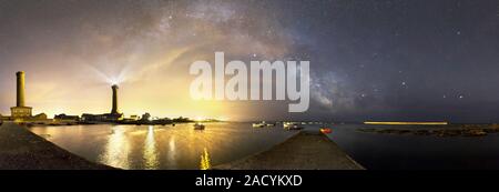 Night sky over a harbour. The Milky Way is seen arching from the Eckmuhl lighthouse. To its right are the constellations Sagittarius and Scorpius and Stock Photo