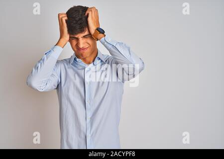 Young indian businessman wearing elegant shirt standing over isolated white background suffering from headache desperate and stressed because pain and Stock Photo