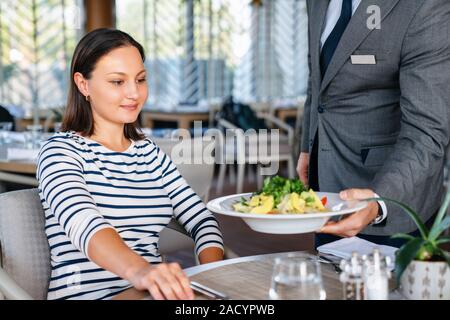 Young woman get served from waiter for a lunch in a elagance restaurant. Stock Photo
