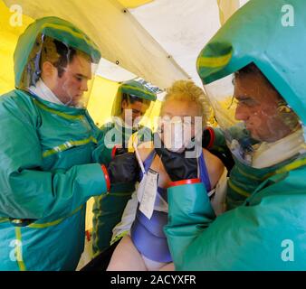 Major emergency decontamination training. Emergency workers in sealed positive pressure protective suits attending to a casualty in a decontamination Stock Photo