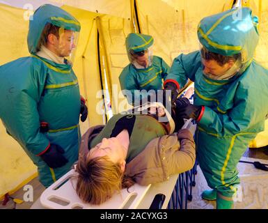 Major emergency decontamination training. Emergency workers in sealed positive pressure protective suits attending to a casualty with simulated injuri Stock Photo