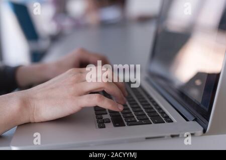 close up of Business womans hand typing on laptop with team on meeting in background Stock Photo