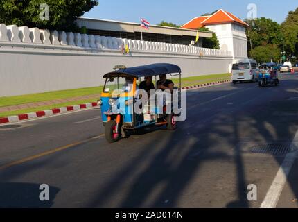 Bangkok, Thailand - December 2, 2019 : Closeup three wheels motor vehicle or tuk tuk running along the street between Wat Pho and Grand Palace wall Stock Photo