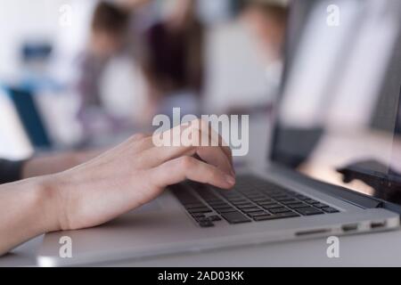 close up of Business womans hand typing on laptop with team on meeting in background Stock Photo