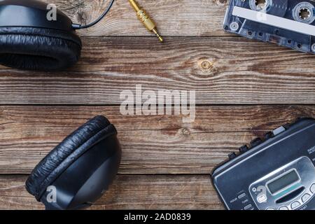 Cassette tapes, cassette player and headphones over wooden table. top view. Stock Photo