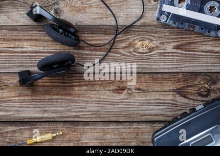 Cassette tapes, cassette player and headphones over wooden table. top view. Stock Photo