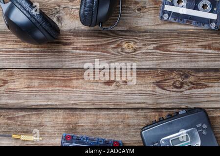 Cassette tapes, cassette player and headphones over wooden table. top view. Stock Photo