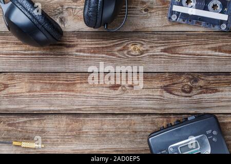 Cassette tapes, cassette player and headphones over wooden table. top view. Stock Photo