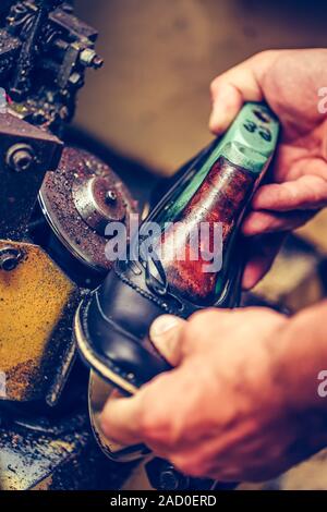 Hands of an experienced shoemaker working in a shoe factory, finishing the soles of the shoes, at a machine. Selective focus Stock Photo