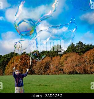 A woman blowing large bubbles in a public park in Bournemouth, UK Stock Photo