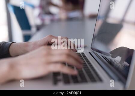 close up of Business womans hand typing on laptop with team on meeting in background Stock Photo