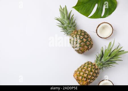 Pineapples, coconuts and palm leaves on white background, space for text Stock Photo
