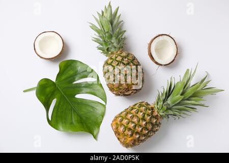 Pineapples, coconuts and palm leaves on white background, top view Stock Photo