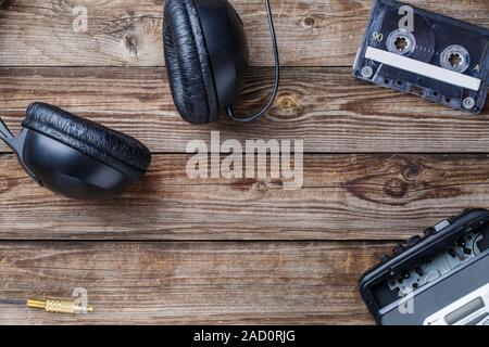 Cassette tapes, cassette player and headphones over wooden table. top view. Stock Photo