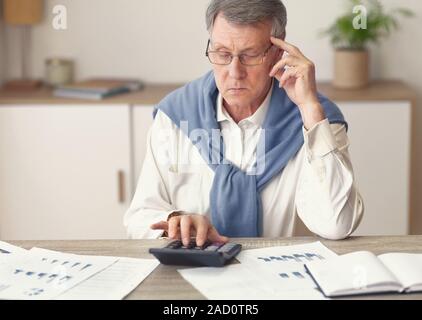 Thoughtful Elderly Businessman Using Calculator Working In Office Stock Photo