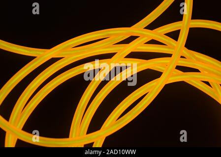 Bright orange luminous wire, twisted light wire, cable. Different shapes and images of lectroluminescent wires with different twists, juicy el wire. Stock Photo