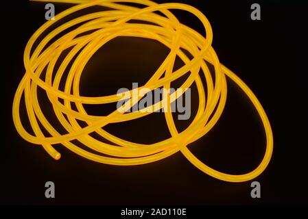 Bright orange luminous wire, twisted light wire, cable. Different shapes and images of lectroluminescent wires with different twists, juicy el wire. Stock Photo