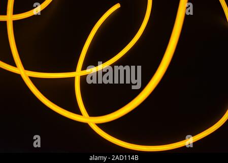 Bright orange luminous wire, twisted light wire, cable. Different shapes and images of lectroluminescent wires with different twists, juicy el wire. Stock Photo