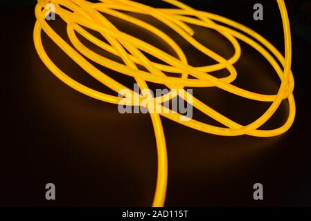 Bright orange luminous wire, twisted light wire, cable. Different shapes and images of lectroluminescent wires with different twists, juicy el wire. Stock Photo