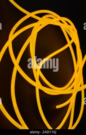 Bright orange luminous wire, twisted light wire, cable. Different shapes and images of lectroluminescent wires with different twists, juicy el wire. Stock Photo