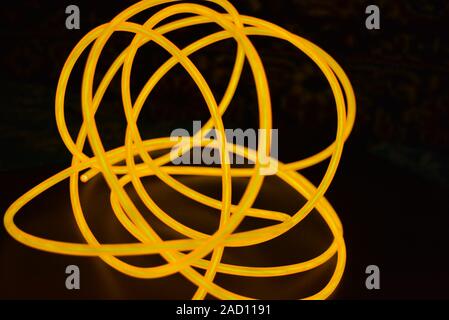 Bright orange luminous wire, twisted light wire, cable. Different shapes and images of lectroluminescent wires with different twists, juicy el wire. Stock Photo