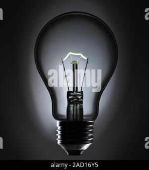 View of an incandescent light bulb. The bulb glows because of a current passing through a thin, coiled tungsten wire. The current heats the wire, maki Stock Photo