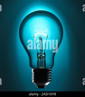 View of an incandescent light bulb. The bulb glows because of a current passing through a thin, coiled tungsten wire. The current heats the wire, maki Stock Photo